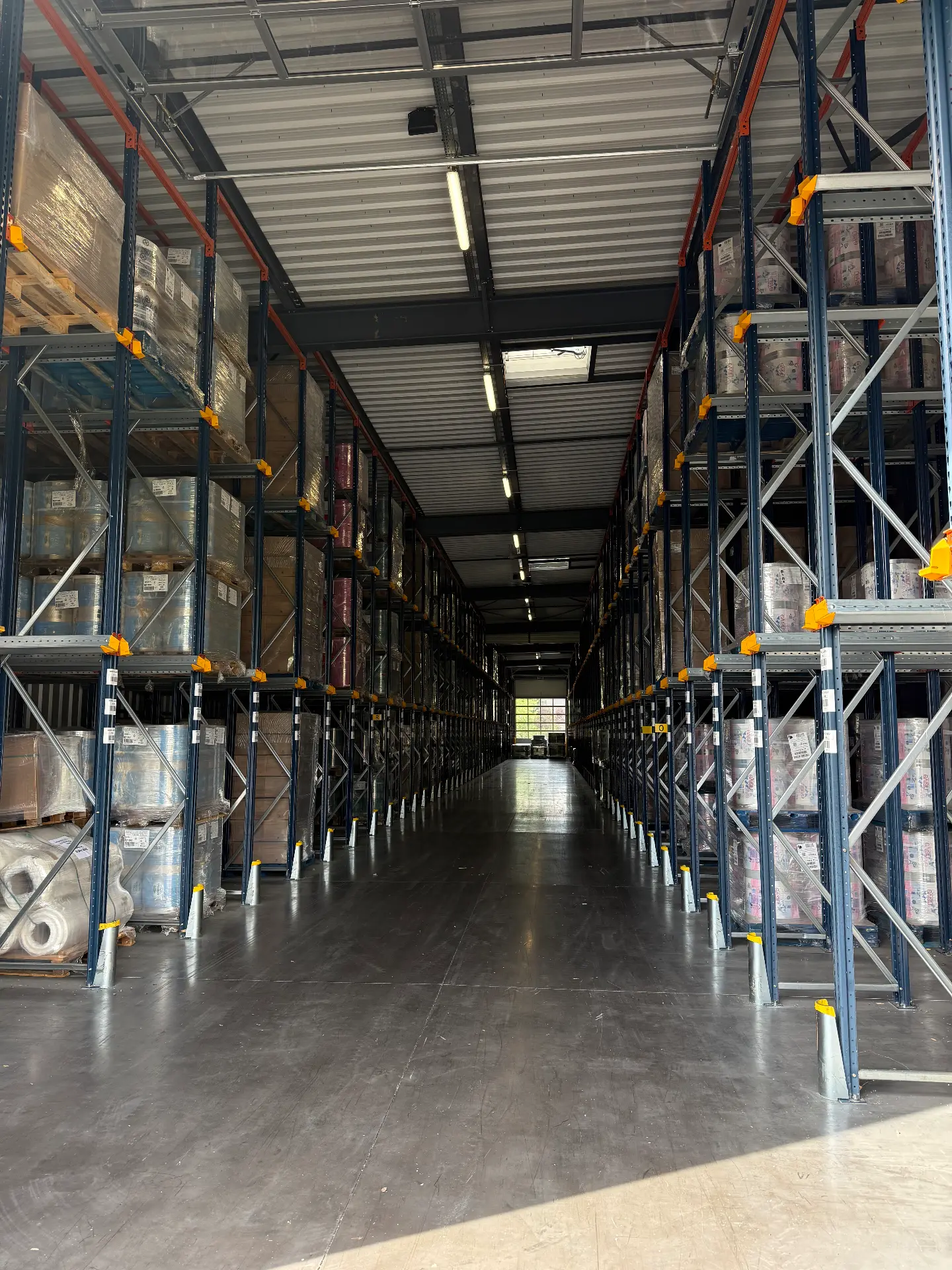 Allée de racks accumulateurs avec bobines et palettes de films techniques